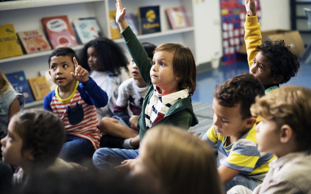 kids in a class. One girl has her hand up